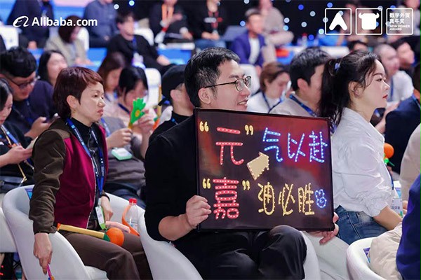 上图为：后援团举出“元气以赴，嘉油必胜”的牌子为杨元嘉加油鼓劲